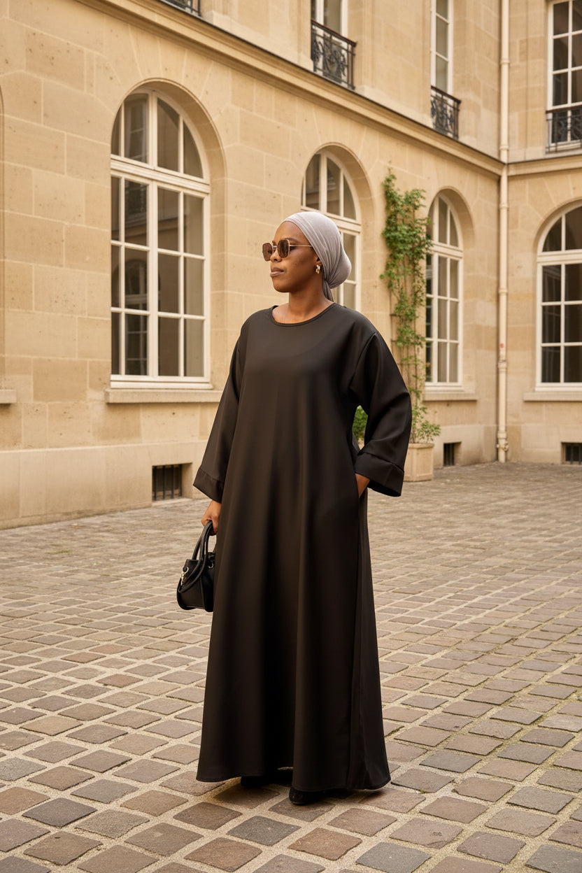 Abaya Mina noire – vue de trois-quarts, dans une cour intérieure