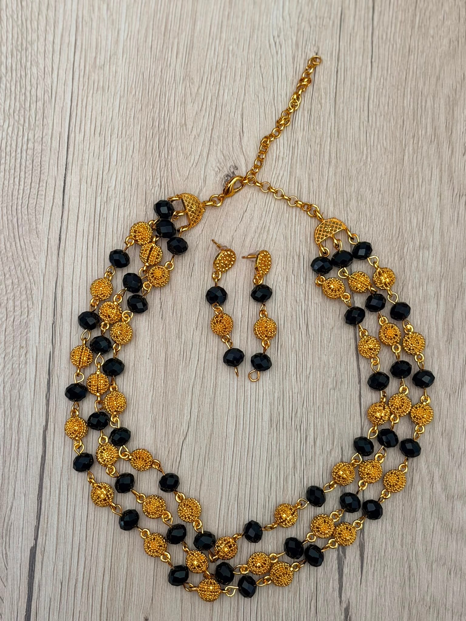 Parure Nadia plaqué or - collier multi-rangs perles dorées et noires facettées avec boucles d'oreilles assorties