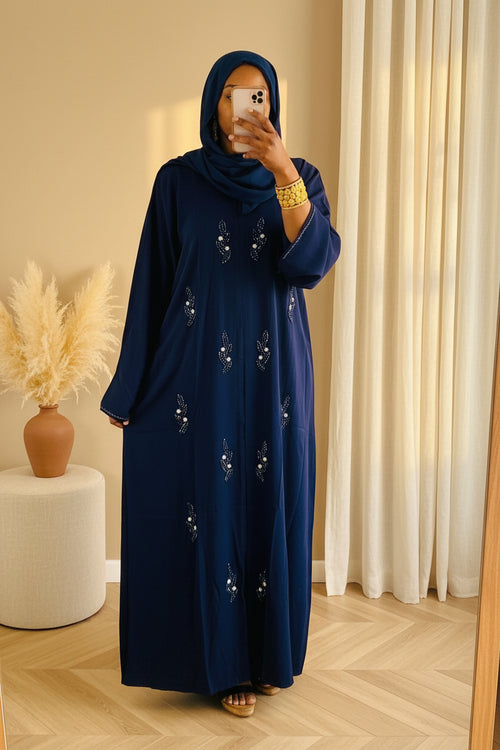 Long navy blue abaya with flowing fabric and delicate floral embroidery on front, worn with matching navy hijab.