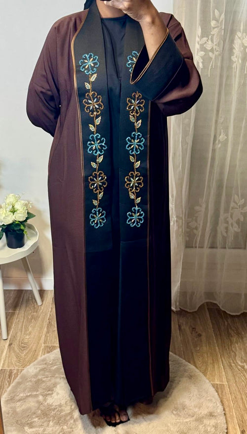 Long brown flowing abaya with wide sleeves and black front panel embroidered with blue and gold floral patterns.