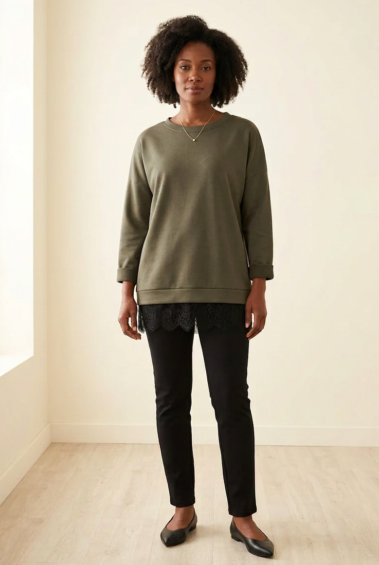 Pull long Aicha kaki porté avec un pantalon noir, coupe oversize et dentelle au bas